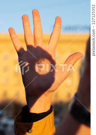 Hand illuminated by sunset with botanical shadow projection 127125352