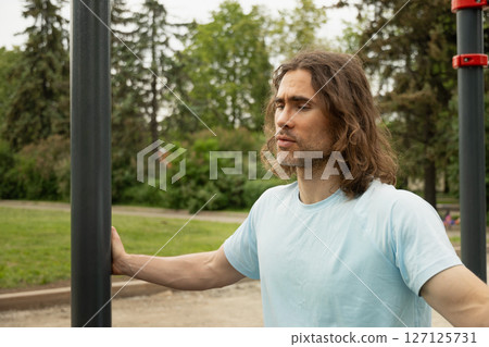 Portrait of tired sporty caucasian man thoughtful expression, lost in thought at public park near sport ground equipment. Laziness, forces himself to exercise. Slow living. Outdoor Portrait of tired sporty caucasian man thoughtful expression, lost in thought at public park near sport ground equipment. Laziness, forces himself to exercise. Slow living. Outdoor 127125731