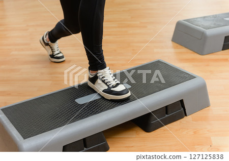 Close-up of female foot in black sneaker on aerobic step. Close-up of female foot in black sneaker on aerobic step. 127125838