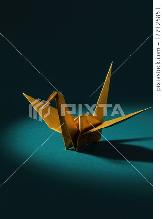 Elegant origami paper crane with dramatic lighting on dark teal background showcasing traditional Japanese folding art and minimalist aesthetic design Elegant origami paper crane with dramatic lighting on dark teal background showcasing traditional Japanese folding art and minimalist aesthetic design 127125851