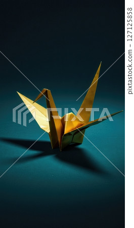 Elegant  origami paper crane with dramatic lighting on dark teal background showcasing traditional Japanese folding art and minimalist aesthetic design 127125858