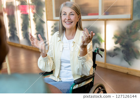 Mid aged woman on a wheelchair looking happy and clapping her hands 127126144