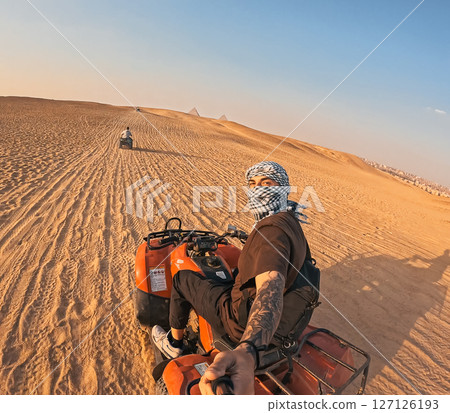 Tourist riding quad bike and taking selfie in desert near giza pyramids 127126193