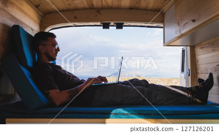 Freelancer working remotely on laptop in camper van at gorafe, spain 127126201