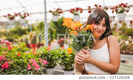 Gardener holding french marigold in greenhouse Gardener holding french marigold in greenhouse 127126208