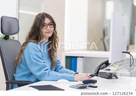 Young office worker typing on keyboard and smiling in modern office Young office worker typing on keyboard and smiling in modern office 127126234
