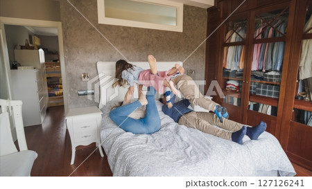 Family enjoying playful moments on bed together Family enjoying playful moments on bed together 127126241