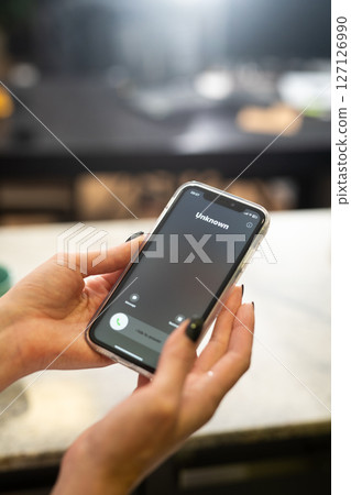 Fraud or fraudulent schemes. Close-up of a woman's hand holding a phone with an unexpected incoming call from an unknown person 127126990