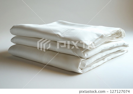 Luxury cotton. Egyptian cotton sheets on a white background. Stack of high-thread-count white sheets. Lifestyle of premium clients. 127127074