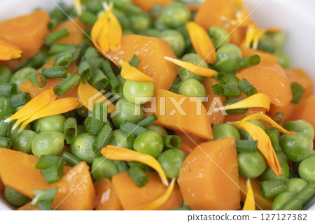 Fresh garden peas and carrots cooked in butter, garnished with chives and marigold flowers for a Fresh garden peas and carrots cooked in butter, garnished with chives and marigold flowers for a 127127382