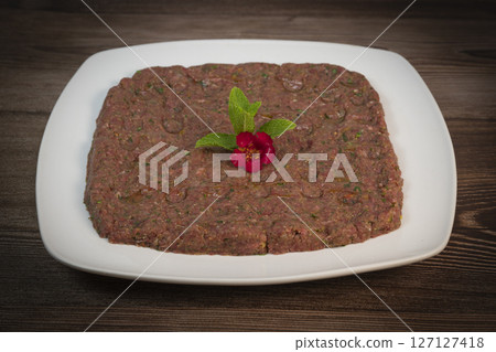 Delicious Lebanese Kebbe Naye garnished with olive oil and fresh mint on a rustic wooden table 127127418
