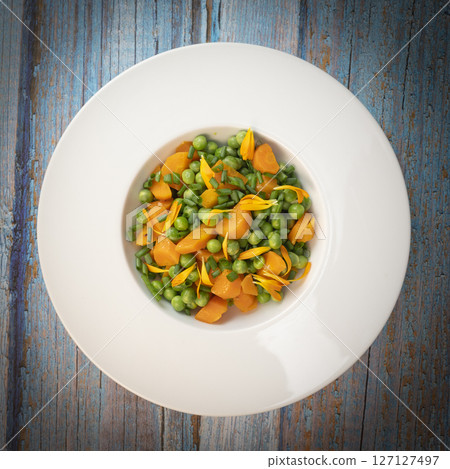 Fresh garden peas and carrots cooked in butter, garnished with chives and marigold flowers for a 127127497