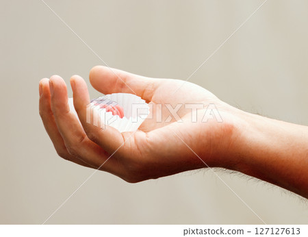 Close-Up of Hand Holding a Small Candy in a Wrapper Close-Up of Hand Holding a Small Candy in a Wrapper 127127613