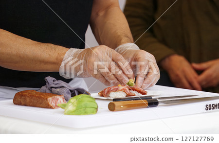 Chef Preparing Sushi Rolls With Fresh Ingredients on a Cutting Board Chef Preparing Sushi Rolls With Fresh Ingredients on a Cutting Board 127127769