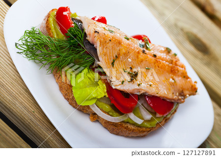 Slice of bread with roasted trout fillet 127127891