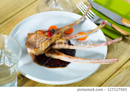 Baked under tasty lamb ribs served with sauce and carrots 127127983