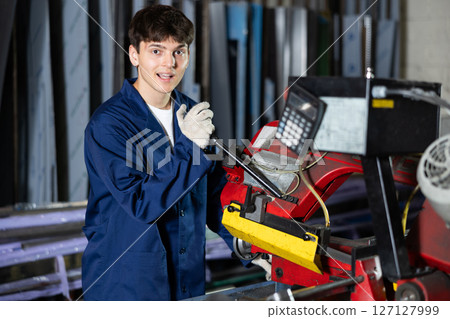 Young guy cuts profile pipe on machine Young guy cuts profile pipe on machine 127127999