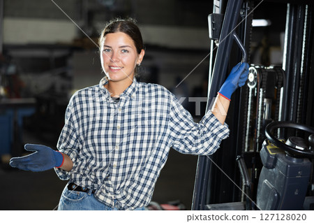 Young woman posing by forklift in workshop Young woman posing by forklift in workshop 127128020