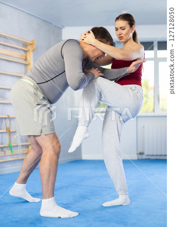 Young girl practicing feet kick method of self-defense in pair with middle-aged man 127128050