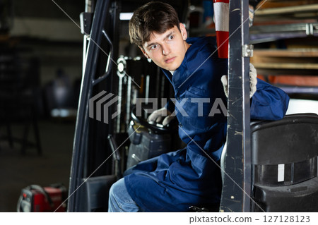 Young male worker working on forklift at metallurgical plant 127128123