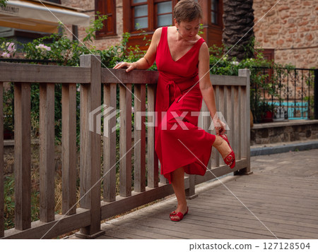 Woman in red dress walking narrow streets of old town Antalya during warm summer evening. Historic atmosphere and Mediterranean charm creates peaceful travel experience. 127128504