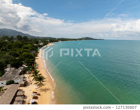 Tropical sandy beach with turquoise sea and palm trees along the shore under a bright sky. Koh Samui, Thailand. Tropical sandy beach with turquoise sea and palm trees along the shore under a bright sky. Koh Samui, Thailand. 127130807