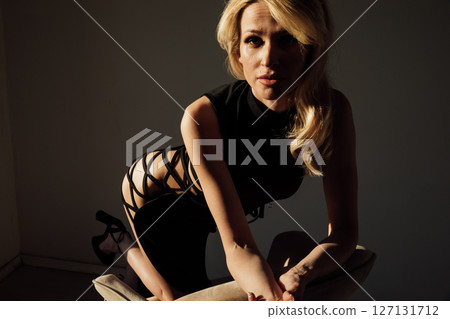 Slim woman in black evening dress sitting on chair Slim woman in black evening dress sitting on chair 127131712