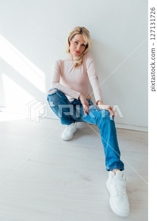 Beautiful fashionable blonde in jeans sitting on the floor 127131726