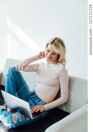 Blonde on couch working on laptop training 127131728