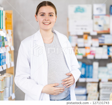 Young pregnant pharmacist welcoming clients in chemist's shop Young pregnant pharmacist welcoming clients in chemist's shop 127131743