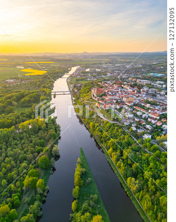 Aerial view reveals the beautiful confluence of the Vltava and Labe rivers close to Melnik, Czechia. Lush green banks and charming towns create a picturesque landscape during sunset. 127132095