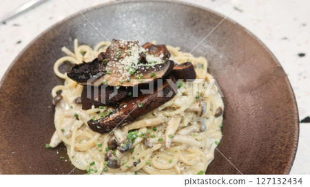 close up of white cream sauce black truffle mushroom pasta spaghetti with copy space 127132434