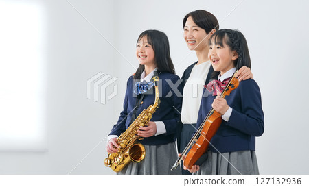 A group of female students and a female teacher with a saxophone and a violin 127132936