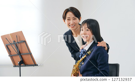 A female teacher instructing a female student on how to play the saxophone 127132937