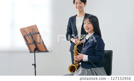 A female teacher instructing a female student on how to play the saxophone 127132938