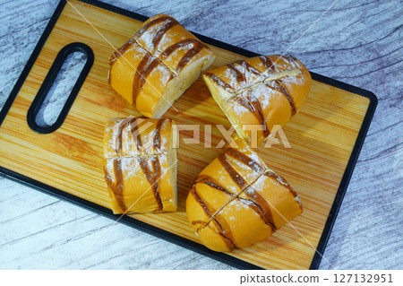 Pieces of a sweet mocha golden loaf with chocolate drizzle and powdered sugar on a wooden board. Pieces of a sweet mocha golden loaf with chocolate drizzle and powdered sugar on a wooden board. 127132951