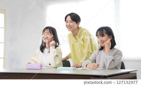 Two girls and a female teacher doing a fist pump while studying 127132977