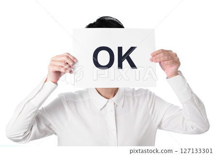 A person in a white shirt holding a piece of paper with the word OK written on it 127133301