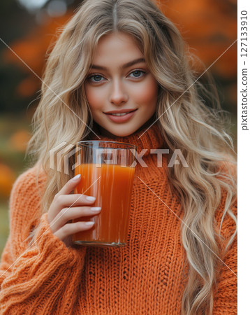 Young woman enjoys a glass of orange drink 127133910