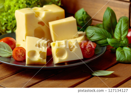 Swiss cheese, green basil, salad, and tomatoes on a wooden table. Swiss cheese, green basil, salad, and tomatoes on a wooden table. 127134127