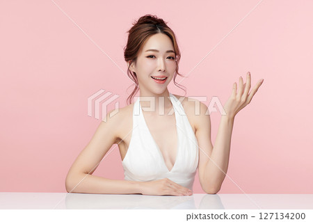 A beautiful young Asian woman with clean, fresh skin against a pink background. Skincare, facial treatment, cosmetology, beauty, and spa. An elegant portrait of an Asian woman. 127134200