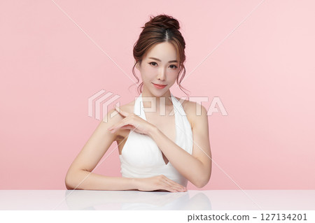 A beautiful young Asian woman with clean, fresh skin against a pink background. Skincare, facial treatment, cosmetology, beauty, and spa. An elegant portrait of an Asian woman. 127134201