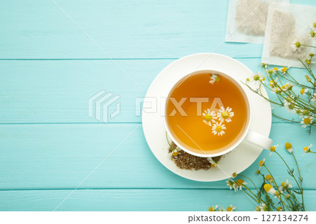 Chamomile tea bag, herbal chamomile tea with fresh daisy flowers on blue wooden background. Immune concept Chamomile tea bag, herbal chamomile tea with fresh daisy flowers on blue wooden background. Immune concept 127134274