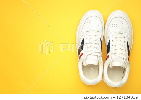 White sneakers, trainers on yellow background. Unisex casual sports shoes. Top view. 127134319
