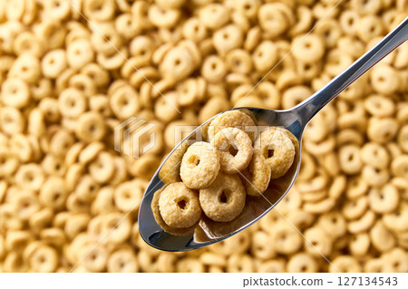 Whole grain cereal rings in a metal spoon of above cereal loops as background. Copy space for text. Whole grain cereal rings in a metal spoon of above cereal loops as background. Copy space for text. 127134543