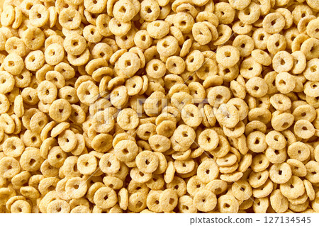 Whole grain cereal rings texture, close up, top view. Crispy healthy cereal rings as background. Whole grain cereal rings texture, close up, top view. Crispy healthy cereal rings as background. 127134545