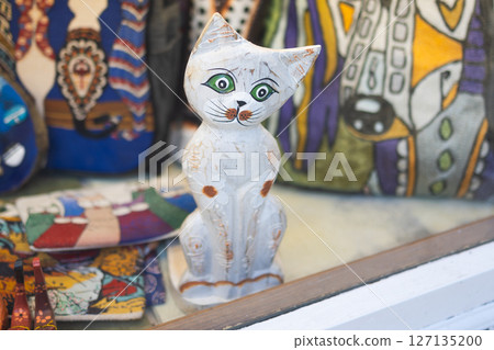 Wooden cat figurine in shop window. Handcrafted toy and folk art concept. 127135200