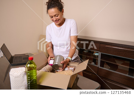 Woman Packing Essentials from Home Desk with Care and Diligence Woman Packing Essentials from Home Desk with Care and Diligence 127135468