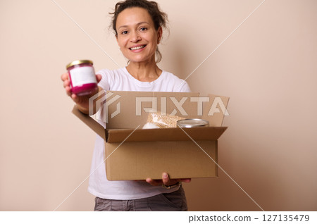 Woman Smiling While Holding Unboxing Gift Box with Glass Jar items Inside 127135479