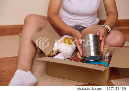 Close-up hands of volunteer woman packing donation box Close-up hands of volunteer woman packing donation box 127135489
